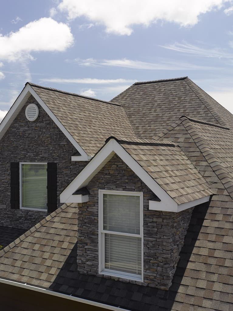 Architectural asphalt shingles with stone veneer siding and crisp white trim